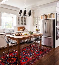 a kitchen with a table, chairs and rug on the floor in front of it