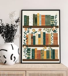 there is a vase with flowers and books on it next to a framed book shelf