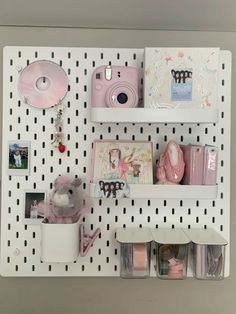 there is a white shelf with many items on it and some pink things hanging from the wall