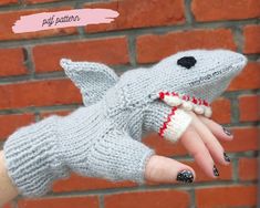 a woman's hand with a knitted animal glove on it, next to a brick wall