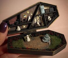 someone is holding up a miniature house in their hand and it looks like they are going to die