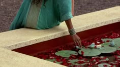 a woman kneeling down next to a pond filled with water lilies