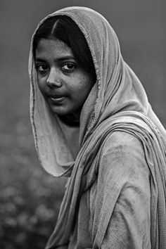 a black and white photo of a woman in a shawl looking at the camera