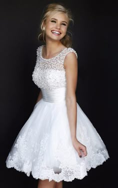 a woman in a short white dress posing for the camera with her hand on her hip