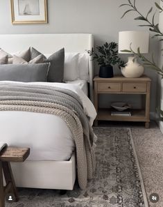 a white bed sitting next to a wooden night stand