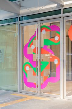 an open door with colorful designs on the glass and metal frame, in front of a building