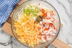 the ingredients for this salad are mixed together in a glass bowl on top of a wooden cutting board