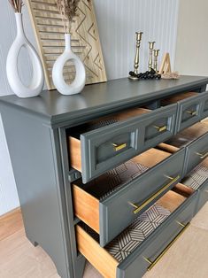 a gray dresser with drawers and vases on top