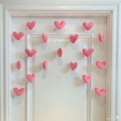 some pink hearts are hanging on a white door