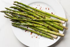 asparagus spears on a white plate with seasoning