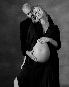 a man and woman pose for a black and white photo while holding their pregnant belly