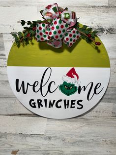 a welcome grinnies sign hanging on the side of a wooden wall with christmas decorations