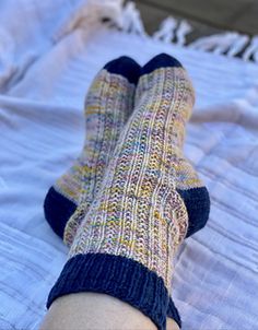 a person's feet with socks on laying on a bed