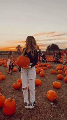 a woman standing in a field full of pumpkins