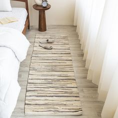 a white bed sitting next to a wooden table on top of a hard wood floor