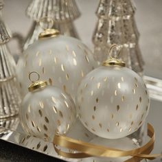 three white glass ornaments on a silver tray