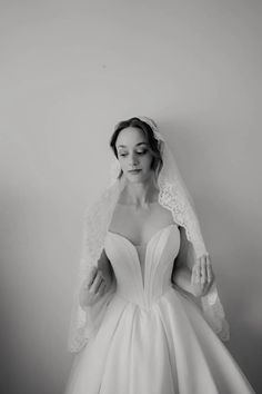 a woman in a wedding dress holding her veil over her head