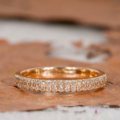 two wedding bands sitting on top of a piece of wood with small diamonds in the middle