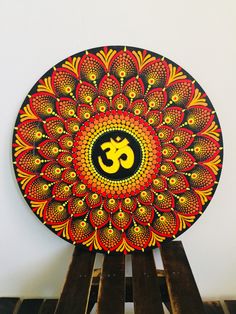 a decorative plate with an om symbol painted on the front and side, sitting on top of wooden pallets