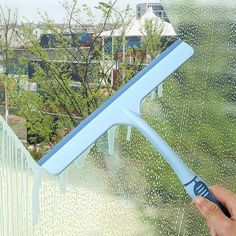 a person is holding a window squirting tool in front of the window outside