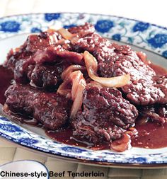 a close up of a plate of food with meat and onions in sauce on it