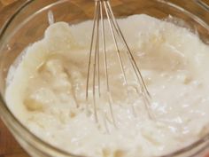 a glass bowl filled with batter and whisk