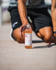 a man kneeling down with a bottle on the ground