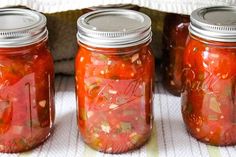 three jars filled with pickles sitting on top of a table