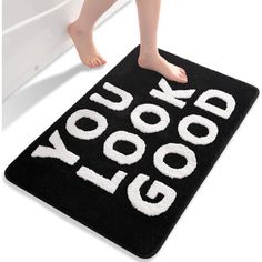 a black door mat with the words you look good on it and a child's feet sticking out