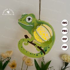 a green chamelon lamp hanging from a string with flowers in front of it