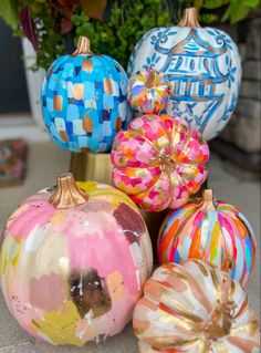 colorful painted pumpkins sitting next to each other in front of a potted plant