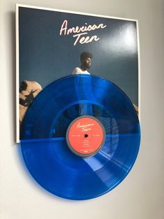 a blue vinyl record with an orange disc on the front and back cover is hanging on a wall