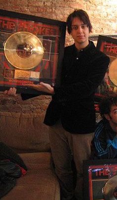 two men standing next to each other holding up some musical instruments in front of them