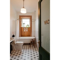 a bathroom with black and white tile flooring next to a bathtub, toilet and sink