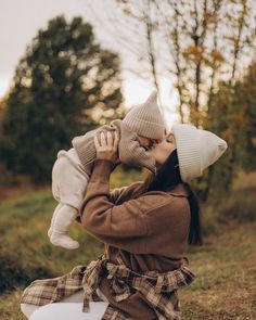 a woman is sitting on the ground holding a baby in her lap and she is wearing a hat