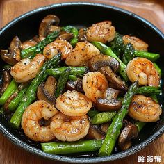 shrimp and asparagus stir - fry in a skillet on a wooden table