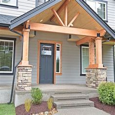 a gray house with a wooden porch and stone steps leading to the front door area