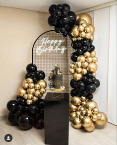 a black and gold balloon arch with happy birthday written on it next to some balloons