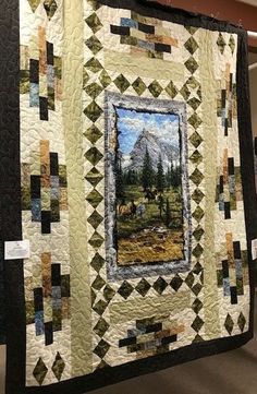 a quilt hanging on the wall in a room with pictures and other items around it