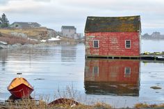 a red house sitting on top of a body of water next to a small boat