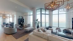 a living room filled with lots of furniture and large windows overlooking the ocean in front of it