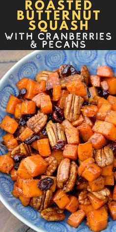 roasted butternut squash with cranberries and pecans in a blue bowl on a wooden table