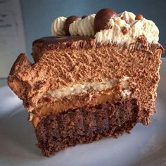 a piece of chocolate cake on a white plate with whipped cream and nuts in the middle