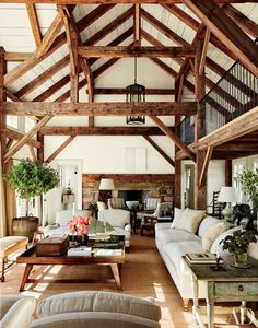 a living room filled with lots of furniture and wooden beams on the ceiling, along with white couches