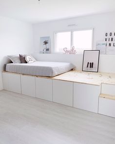 a bed sitting on top of a wooden platform in a bedroom next to a window