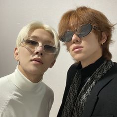 two young men with sunglasses on their faces posing for the camera, both wearing black and white