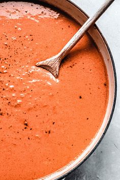 a bowl of tomato soup with a wooden spoon in it