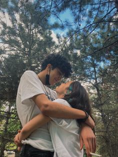 a man and woman embracing each other in the woods