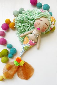 a doll laying on top of a pile of pom poms