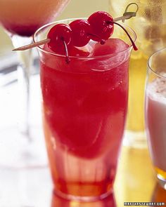 two glasses filled with different types of drinks and one has cherries on the rim